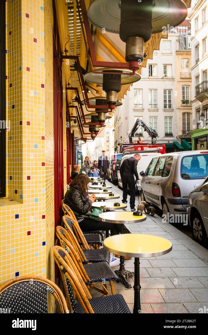 Les gens marchent et s'assoient dans un restaurant en plein air dans le quartier du Marais à Paris, France. Banque D'Images