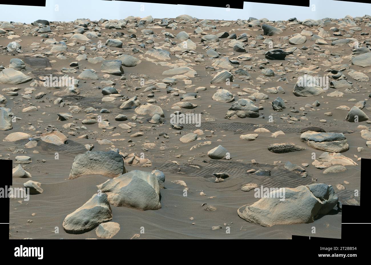 . Perseverance voit Jezero Boulder Field. Cette image composite capturée par le rover Perseverance Mars de la NASA montre des rochers qui décorent le sommet du gisement de fan du cratère Jezero. Les tracés du Rover au milieu de l'image donnent une impression d'échelle. Ces rochers ont été transportés par une eau qui était plus profonde ou coulait plus vite que l'ancienne voie navigable qui déposait les petits cailloux qui peuplaient également la région. Parce que ces rochers sont assis sur les cailloux, les scientifiques croient qu'ils sont arrivés plus tard, peut-être beaucoup plus tard. Le système de caméra Mastcam-Z de Perseverance a pris la série d'images t Banque D'Images