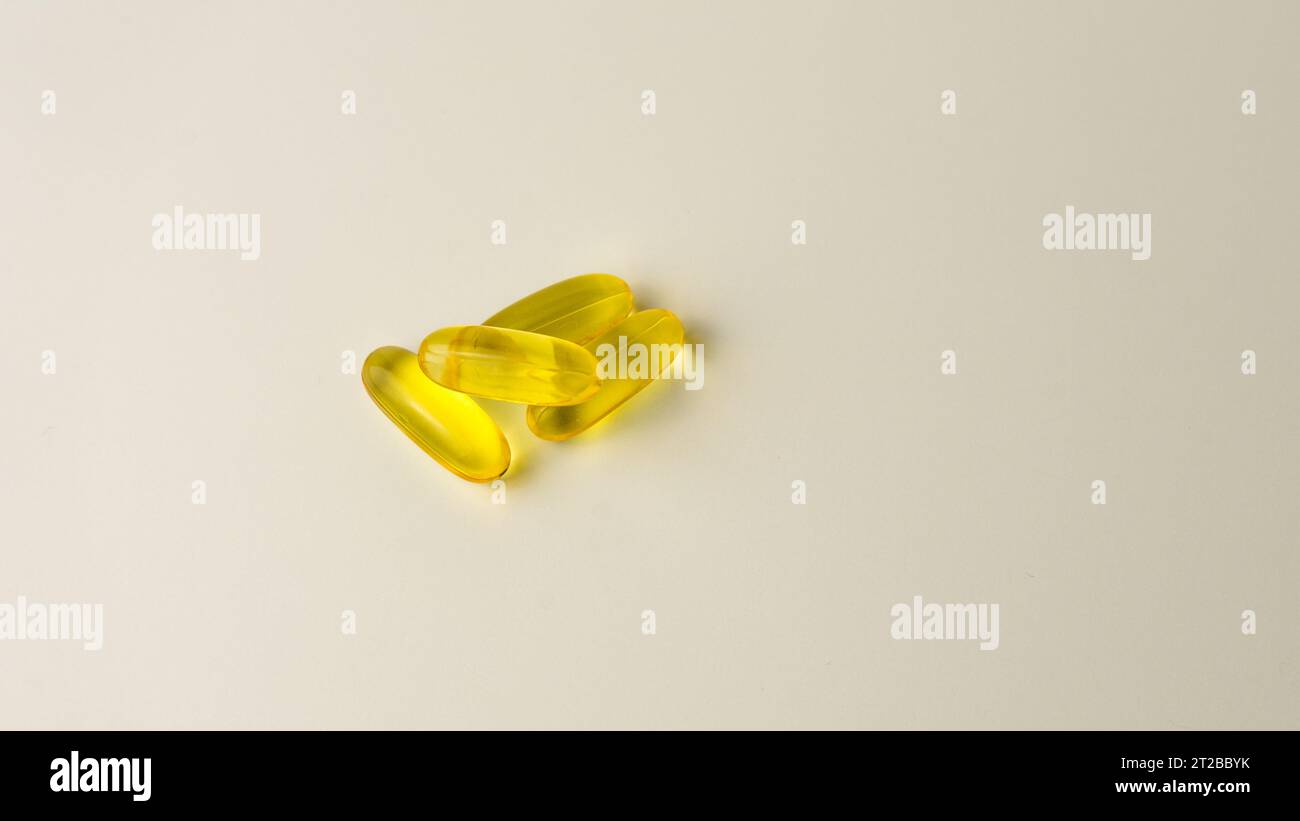 Capsules de saumon sauvage et d'huile de poisson riches en oméga-3 présentées sur un fond blanc cassé doux. Banque D'Images