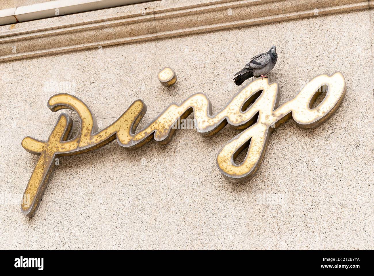 Signalisation dorée avec pigeon sur une façade de bâtiment Banque D'Images