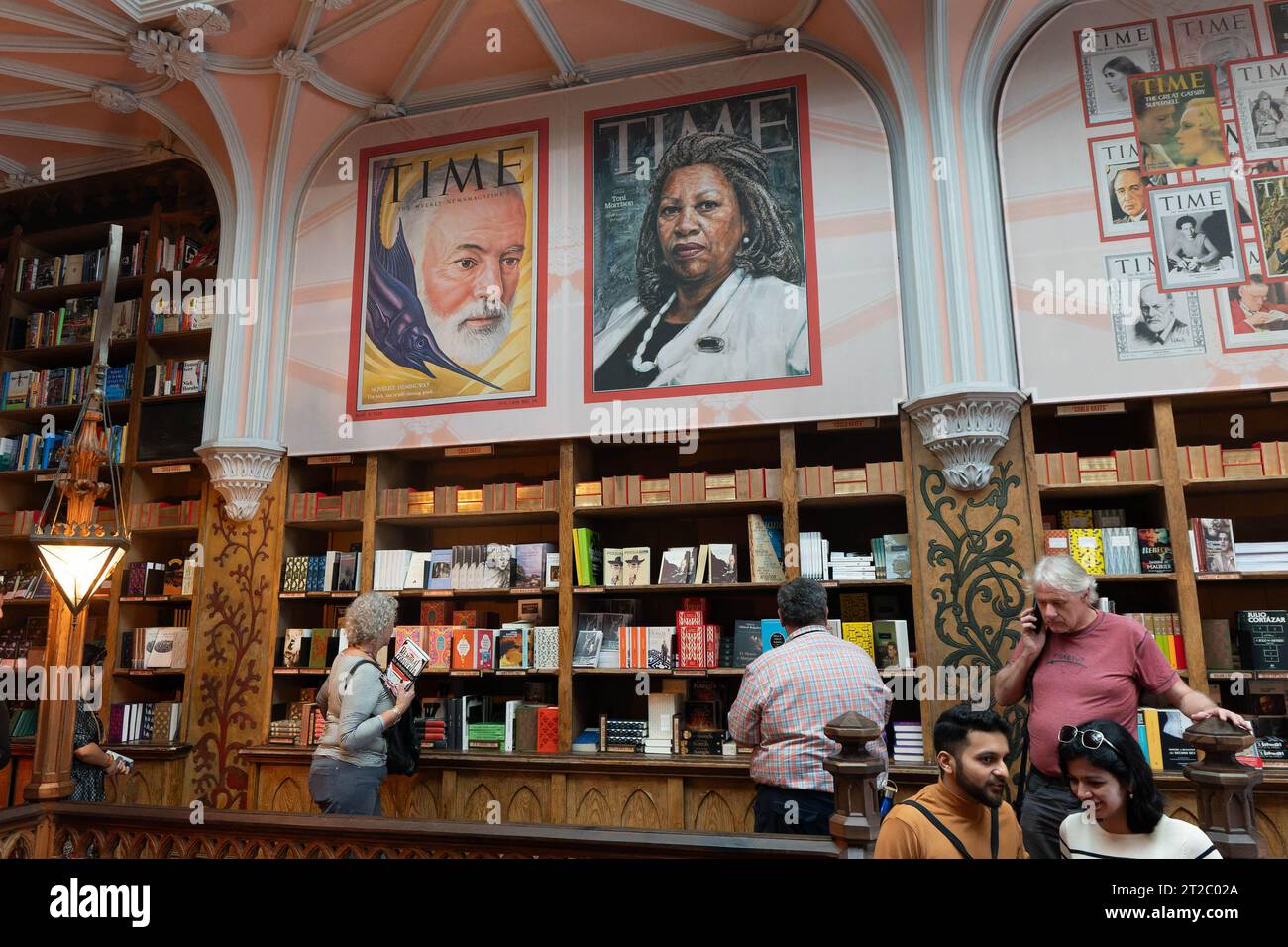 Les clients parcourent des livres dans une librairie historique, Livraria Lello, intérieur avec des couvertures de magazine Time exposées Banque D'Images