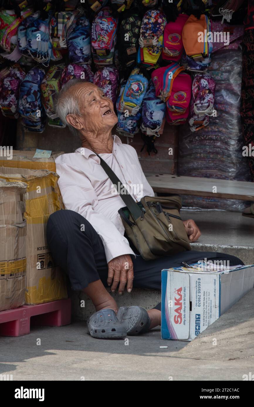 Vieil homme vietnamien assis dans le marché Banque D'Images