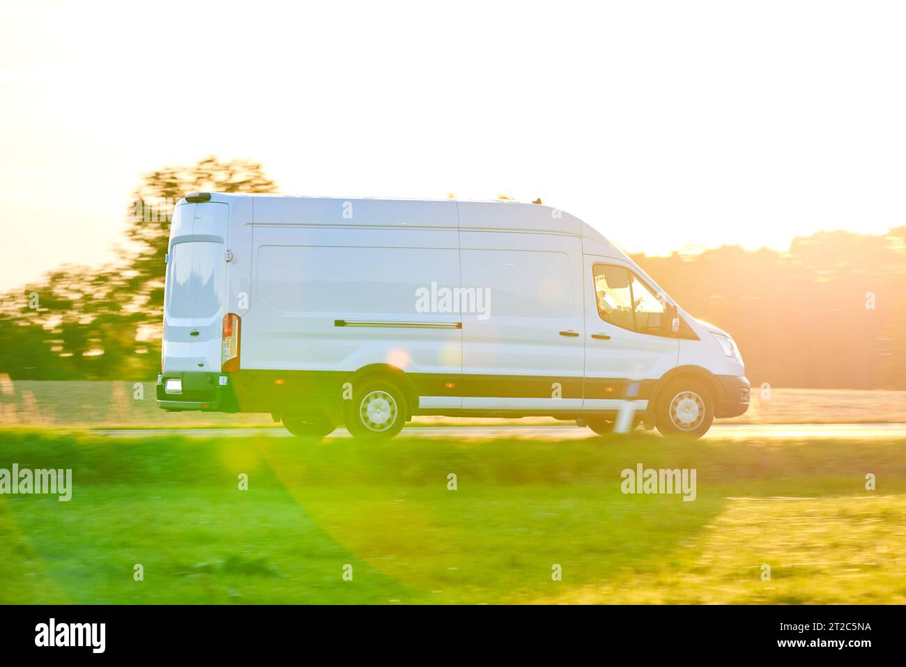 White Van conduisant rapidement sur une route de campagne. Livraison Van conduisant au coucher du soleil en saison d'automne. Banque D'Images