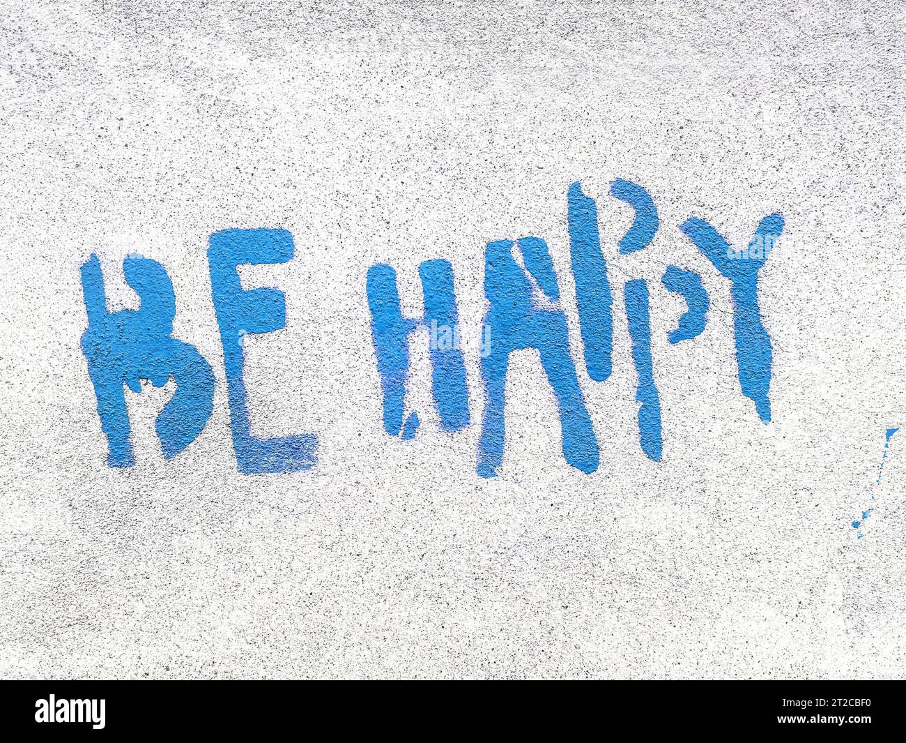 Bleu Be Happy écrit dans le style graffiti avec texture rugueuse isolée sur fond gris. Banque D'Images