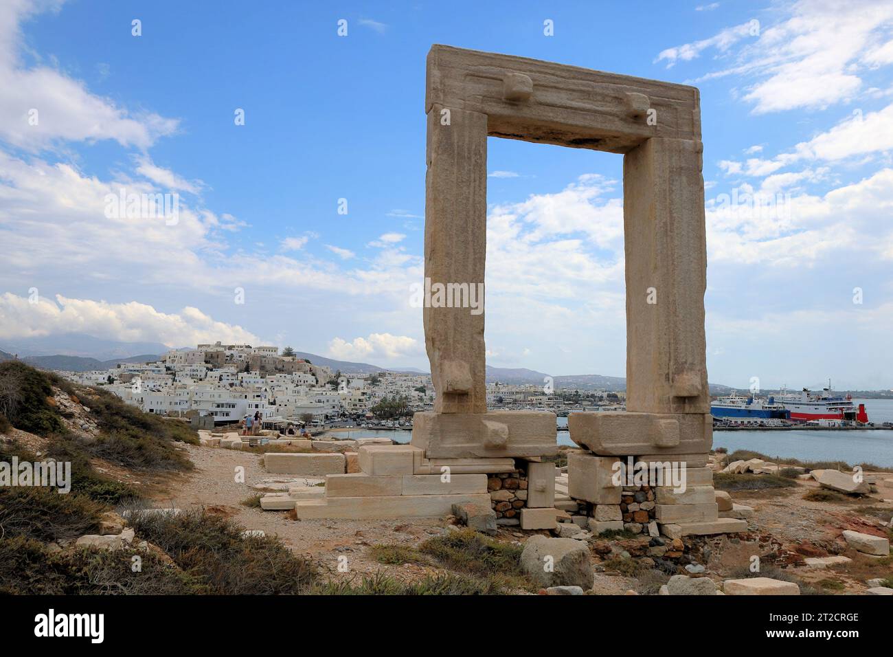 Naxos Portara : la grande porte de Naxos, vestiges d'un ancien temple sur l'île de Palatia, avec la ville moderne en arrière-plan. Banque D'Images
