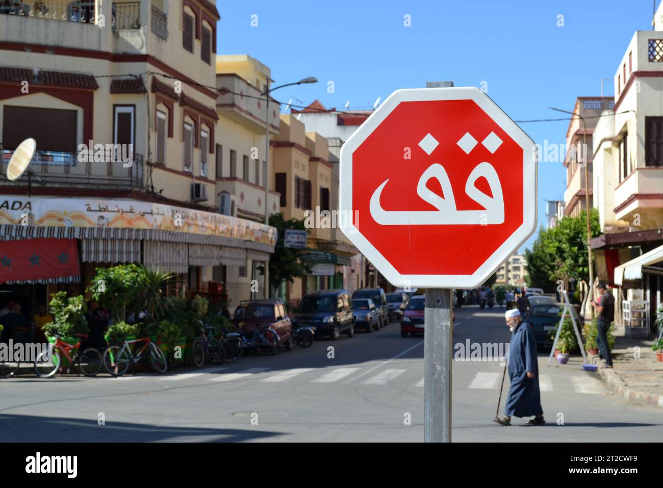 EL KSAR EL KEBIR, MAROC - 10 NOVEMBRE 2015 : panneau de signalisation ARRET arabe avec un vieil homme en arrière-plan dans la ville marocaine d'El Ksar El Kebir. Banque D'Images