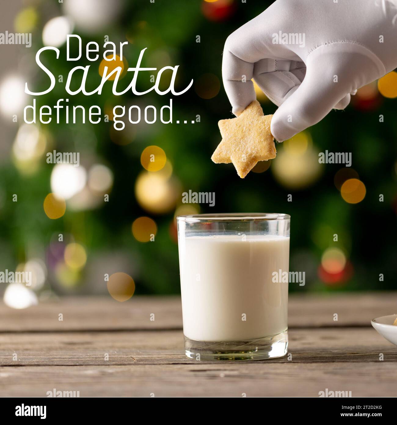 Composite de biscuit blanc en forme d'étoile plongeant à la main dans le verre de lait et cher père noël définissent le bon texte Banque D'Images
