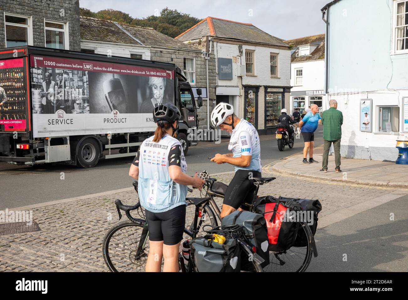 Homme et femme avec des vélos de tourisme portant des dossards Tour of Britain à Padstow Cornwall, septembre 2023, Angleterre Banque D'Images