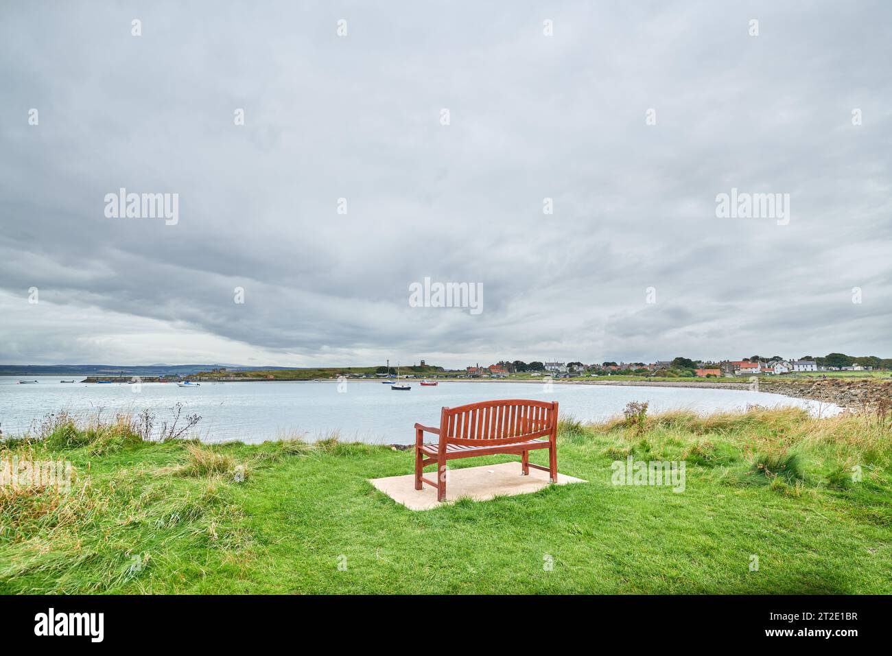 Banc vide au bord de la mer près du port sur l'île Sainte de Lindisfarne, Northumberland, Angleterre. Banque D'Images