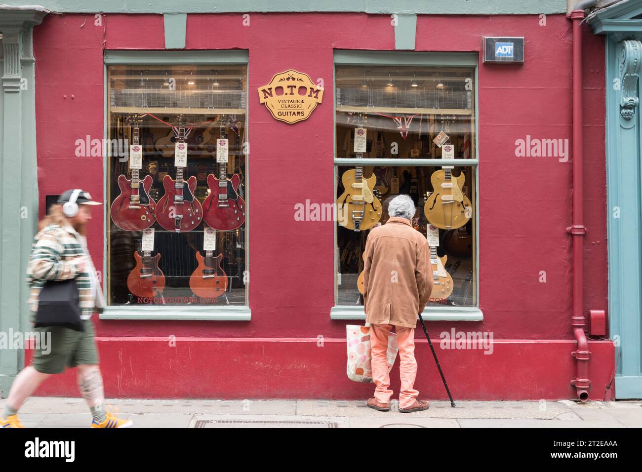 Un homme âgé avec un bâton de marche faisant du shopping à la fenêtre au no. Tom Guitars, Denmark Street, Londres, WC2, Angleterre, ROYAUME-UNI Banque D'Images