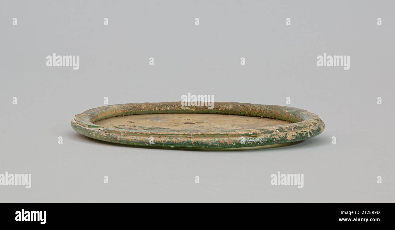 Couvercle en verre Roman 1st Century ce bleu vert translucide.disque en forme, fragment légèrement concave avec épais, double pli autour du bord.écaillé, bord altéré à plier ; piqûres, ternissement et incrustation brun limpide sur la surface supérieure concave.ce disque semble avoir été fabriqué à partir d'un plus grand récipient, coupé vers le bas pour faire un couvercle concave peu profond. Il peut avoir été utilisé pour couvrir une urne cinéraire en verre. Afficher plus. Couvercle en verre. Roman. 1st Century EC. Verre ; soufflé. Early Imperial. Verre Banque D'Images