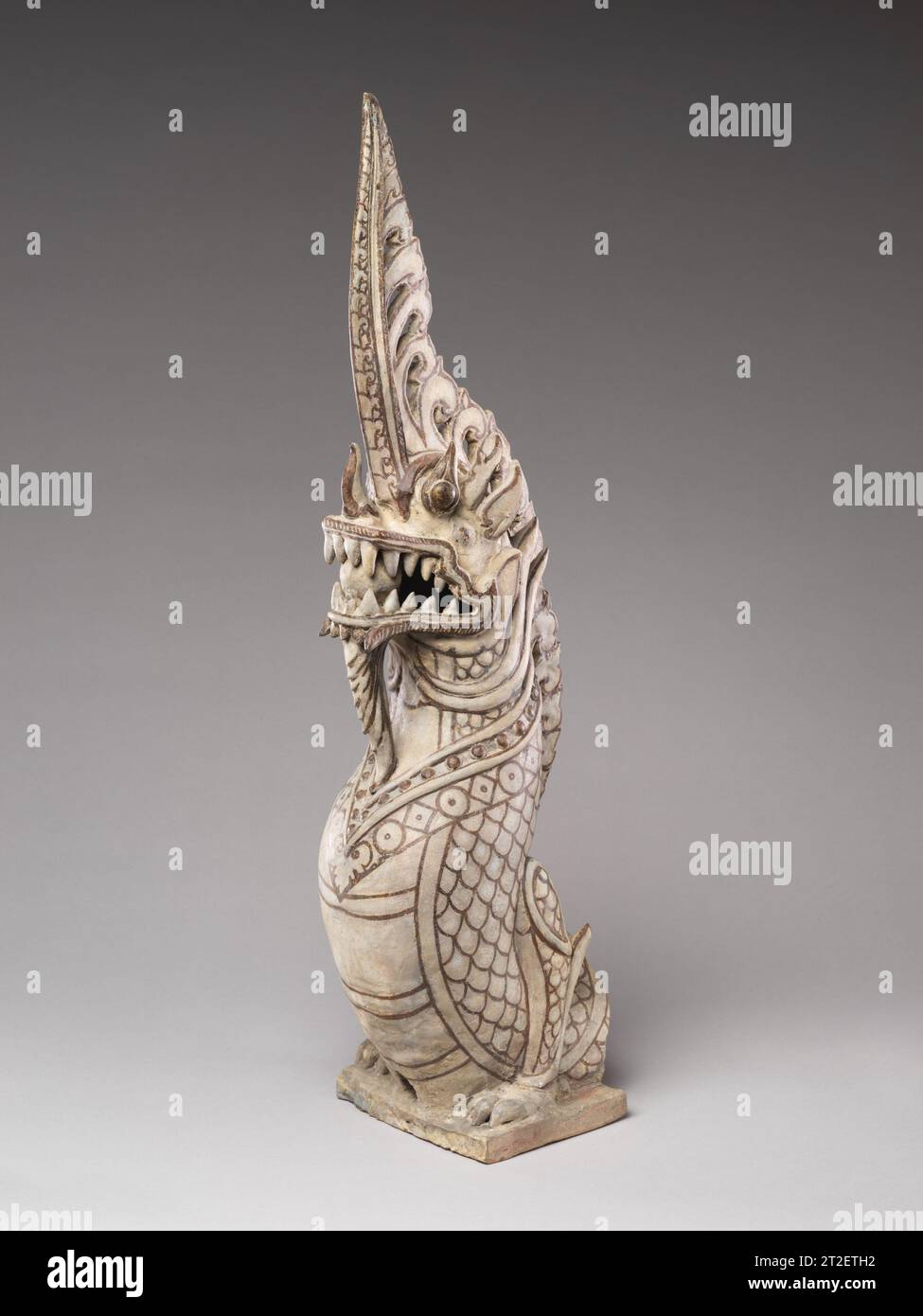 Antefix architectural en forme de funial makara Nord-central Thaïlande, Sukhothai fours fin 14e-15e siècle ce funial architectural pour un temple a pris la forme d'une créature mythique dragon, clairement dérivée du makara indic mais avec de forts éléments indigènes, comme l'importance accordée au corps ressemblant à un serpent plutôt qu'à celui du crocodile plus traditionnel. Ici, le dragon barbu semble émerger des mâchoires d'un makara, représenté à la base du funial. Le bâtiment du temple à Sukhothai était à la fois en latérite et en briques cuites, rendu avec un épais habillage de stuc an Banque D'Images