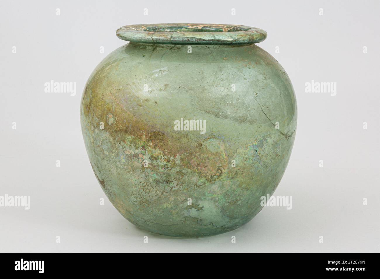 Urne cinéraire en verre (olla) romaine mi-1e–2e siècle ce bleu-vert translucide.large, bord horizontal, avec bord tubulaire arrondi fait par pliage, vers le bas et vers l'intérieur ; corps ovoïde ; concave profond bottom.Complete sauf pour une puce altérée sur le bord intérieur de la jante, avec de nombreuses fissures dans la jante, plusieurs s'étendant vers le bas ; beaucoup de bulles; ternissement, légère incrustation et faible iridescence à l'extérieur, piqûres profondes, incrustation limpide et intempéries irisées brillantes à l'intérieur. Afficher plus. Urne cinéraire en verre (olla). Roman. Milieu du 1e au 2e siècle de notre ère. Verre ; soufflé. Moyen impérial. Verre Banque D'Images