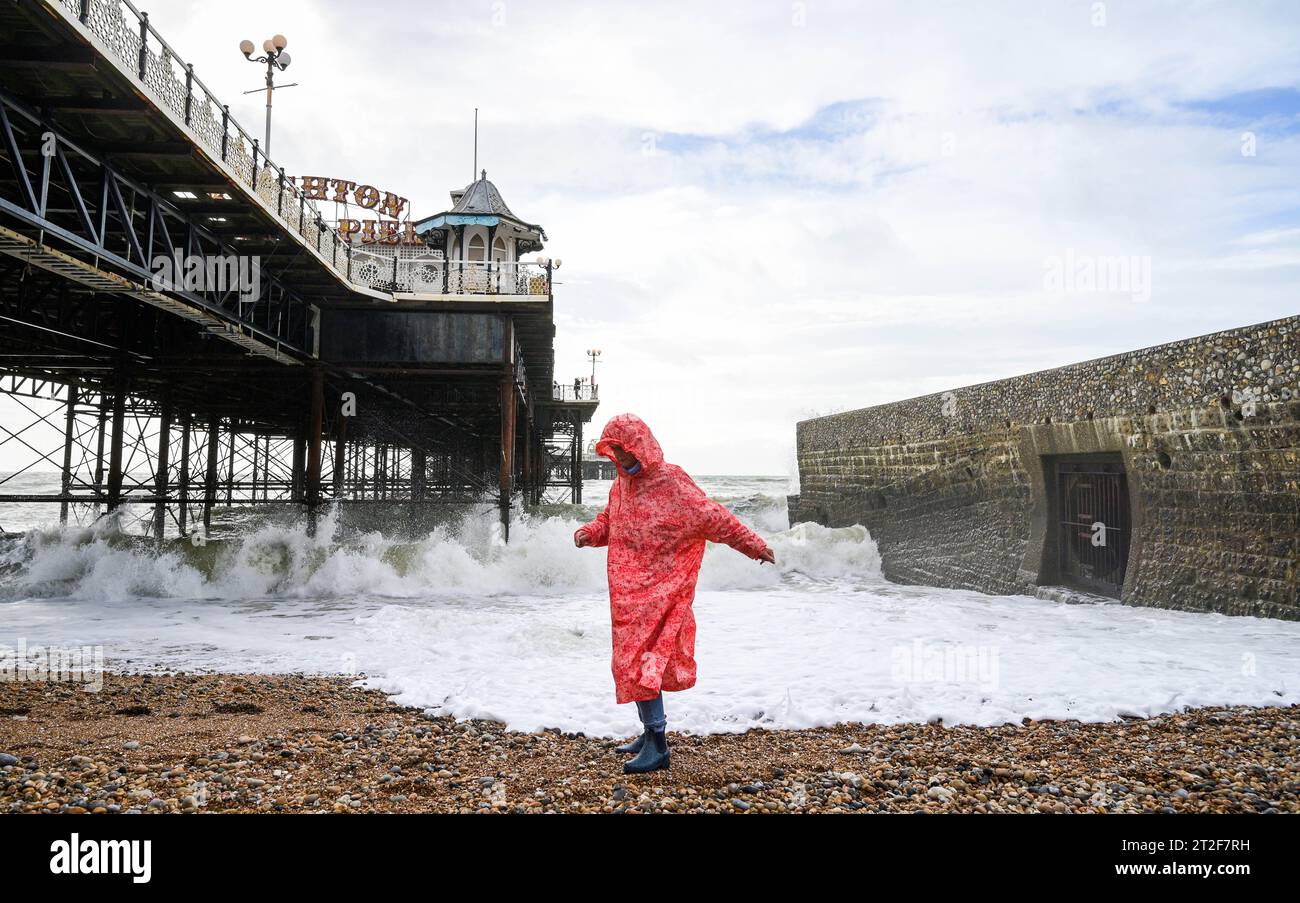 Brighton Royaume-Uni 19 octobre 2023 - Un marcheur sur la plage de Brighton par la jetée sur une journée venteuse le long de la côte sud alors que Storm Babet frappe des parties de la Grande-Bretagne avec des avertissements météorologiques rouges émis en Écosse : Credit Simon Dack / Alamy Live News Banque D'Images