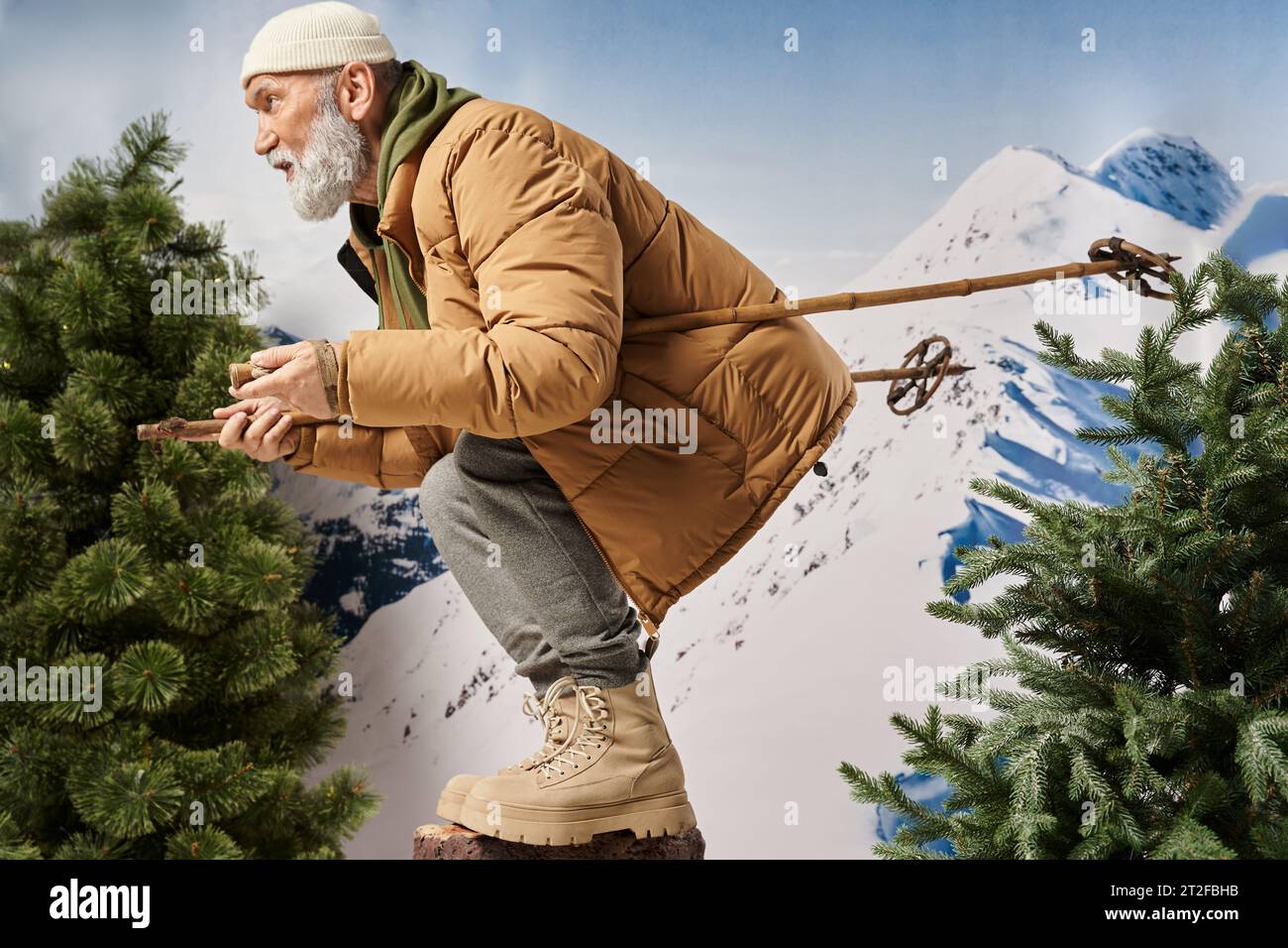 Homme barbu sportif habillé comme le Père Noël accroupi avec des bâtons de ski posant dans le profil, concept d'hiver Banque D'Images