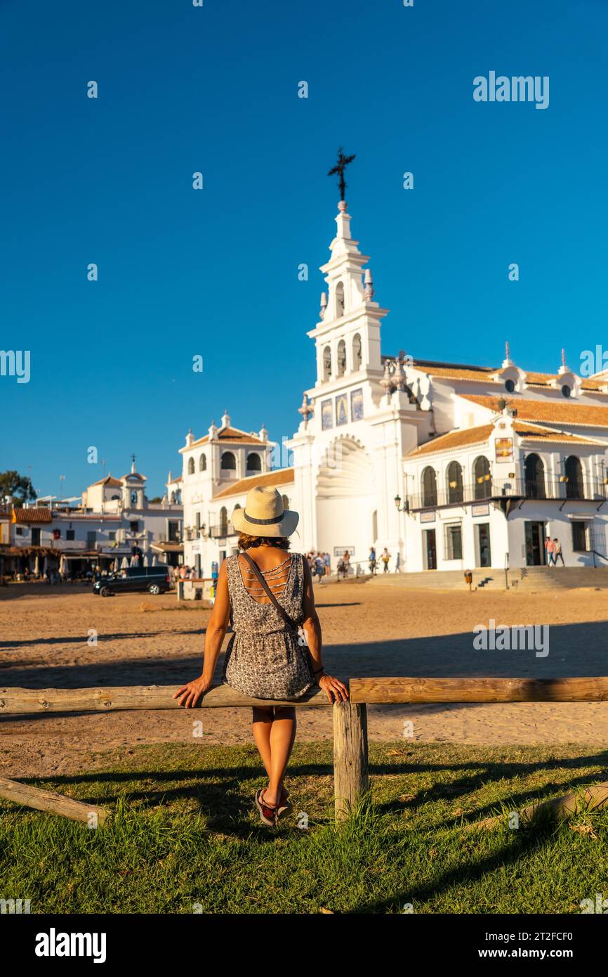 Une jeune femme avec un chapeau assise et regardant le sanctuaire El Rocio au festival Rocio, Huelva. Andalousie Banque D'Images