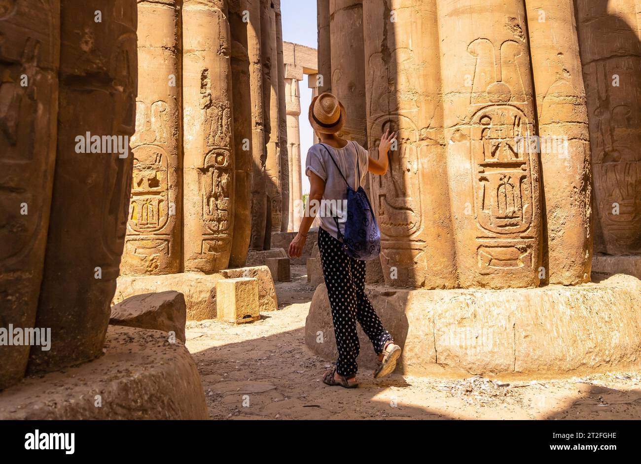 Un jeune touriste dans un t-shirt blanc et chapeau regardant des dessins égyptiens antiques sur les colonnes du Temple de Louxor, Egypte Banque D'Images