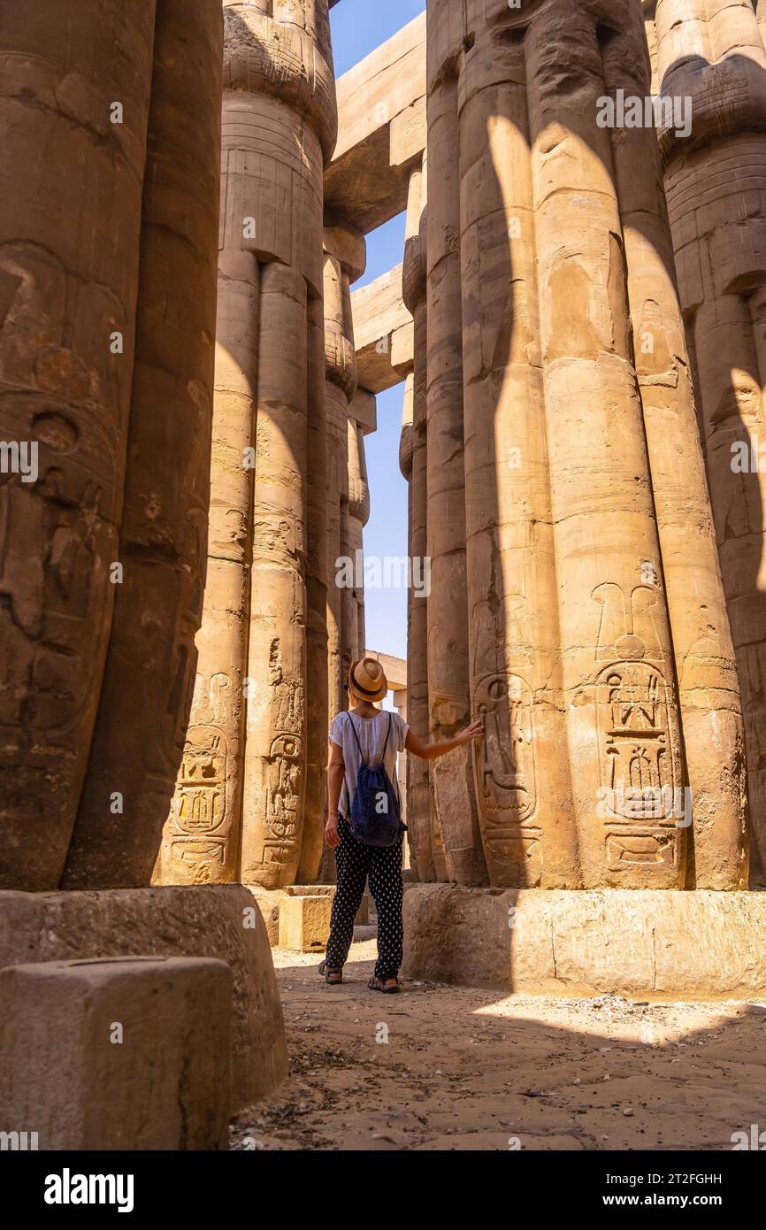 Un jeune touriste dans un t-shirt blanc et chapeau regardant des dessins égyptiens antiques sur les colonnes du Temple de Louxor, Egypte Banque D'Images