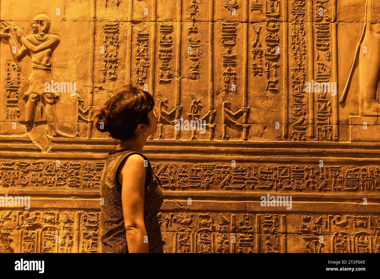 Une jeune femme regardant des dessins égyptiens et des hiéroglyphes au temple de Kom Ombo, le temple dédié aux dieux Sobek et Horus. En ville Banque D'Images
