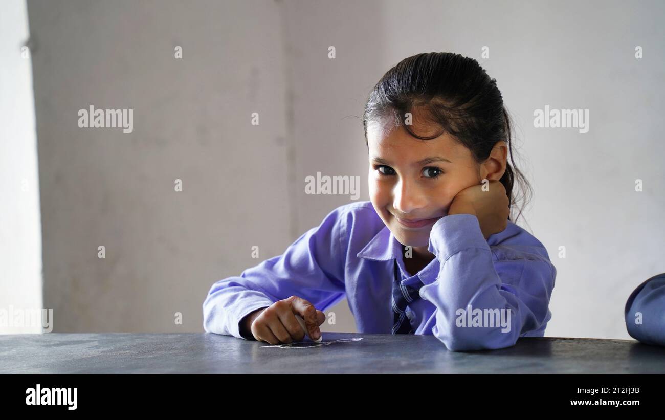 Portrait de l'enfant heureux de l'école indienne assis au bureau dans la salle de classe, les enfants de l'école avec des stylos et des cahiers test d'écriture École élémentaire, éducation conc Banque D'Images