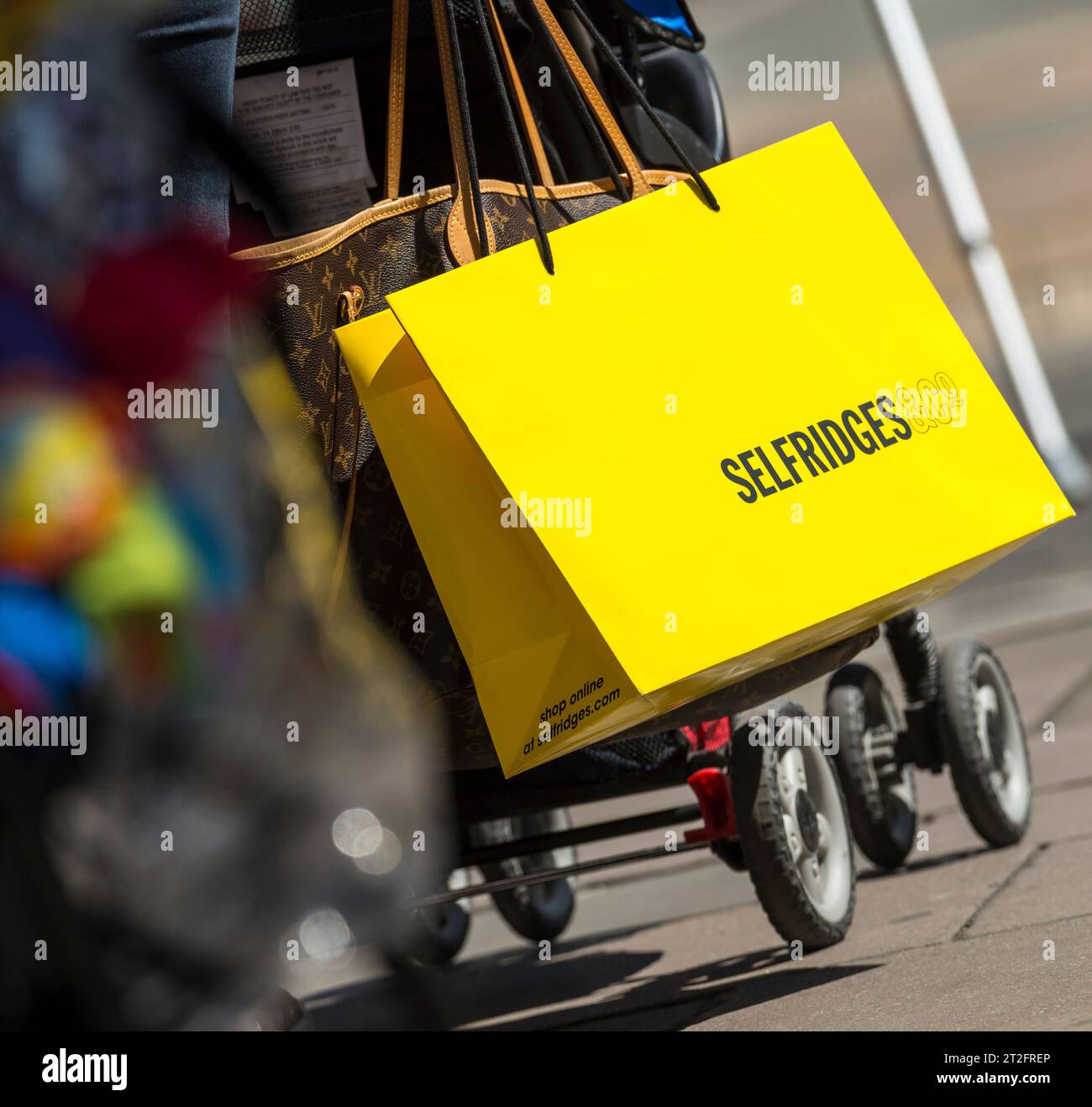Gros plan d'un sac Selfridges jaune sur une poussette dans le centre de Londres, capturant le commerce de luxe et le style de vie des consommateurs au Royaume-Uni. Banque D'Images