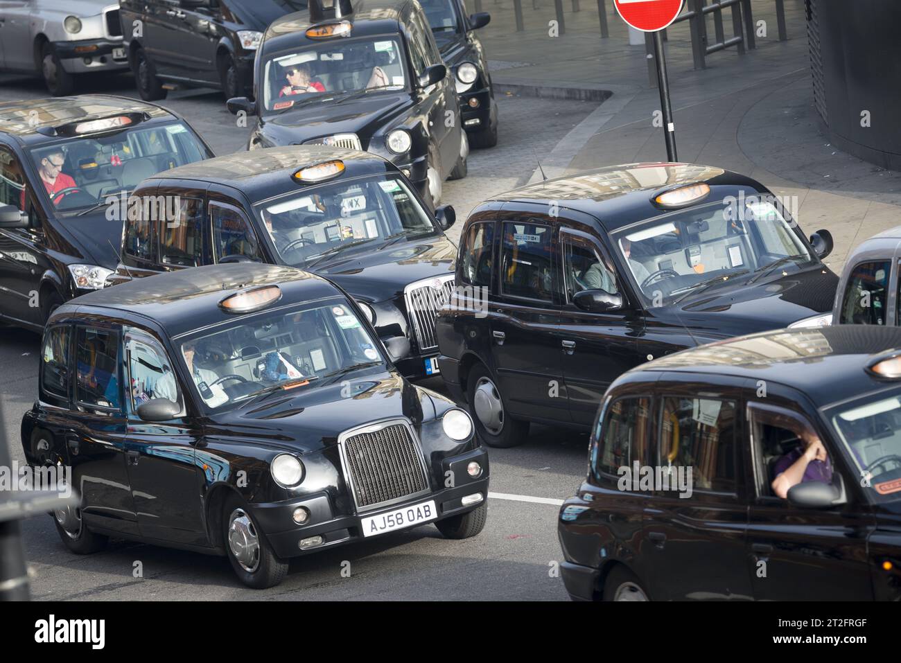Trafic intense de taxis noirs emblématiques de Londres dans une rue animée du centre de Londres, illustrant les transports urbains britanniques et la congestion Banque D'Images