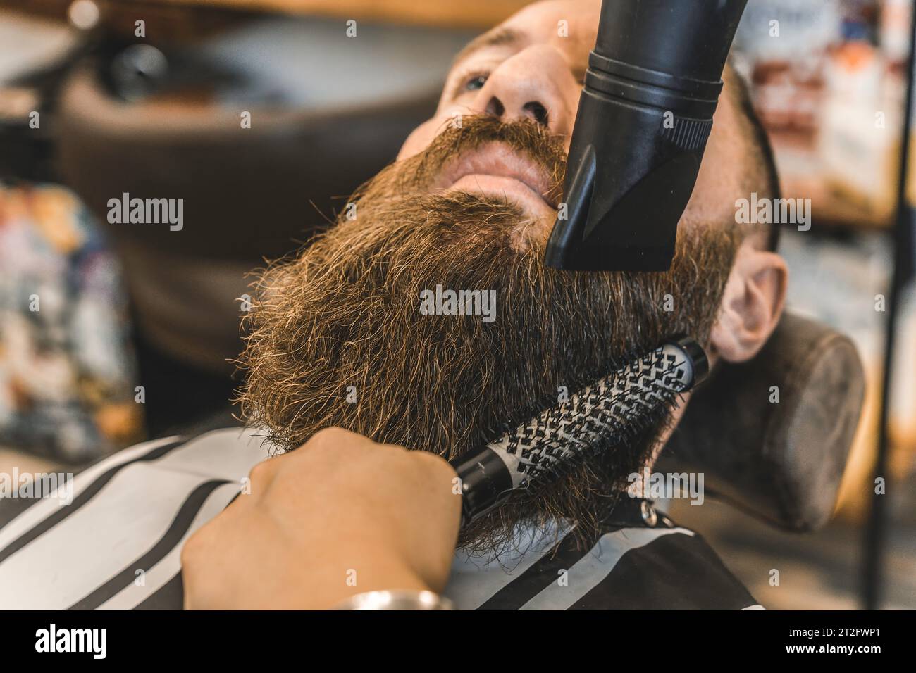 Coiffeur féminin utilisant le sèche-cheveux pour lisser sa longue barbe - Hipster homme au salon de coiffure obtenir la barbe et les cheveux coupés - salon de coiffure concep Banque D'Images