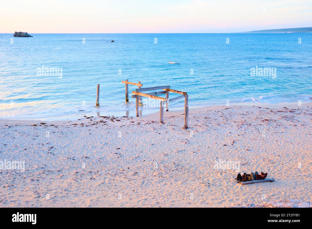 Restes de la vieille jetée et deux personnes regardant le coucher de soleil à Hamelin Bay dans la région sud-ouest de l'Australie occidentale. Banque D'Images