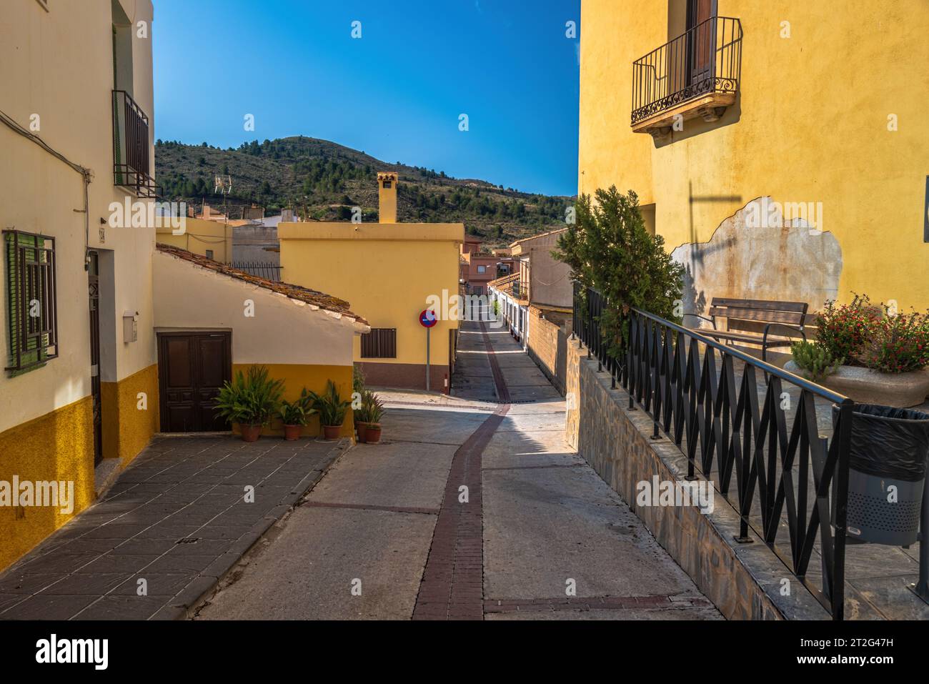 Une photo grand angle d'une rue de village espagnol menant au pied d'une montagne. Banque D'Images
