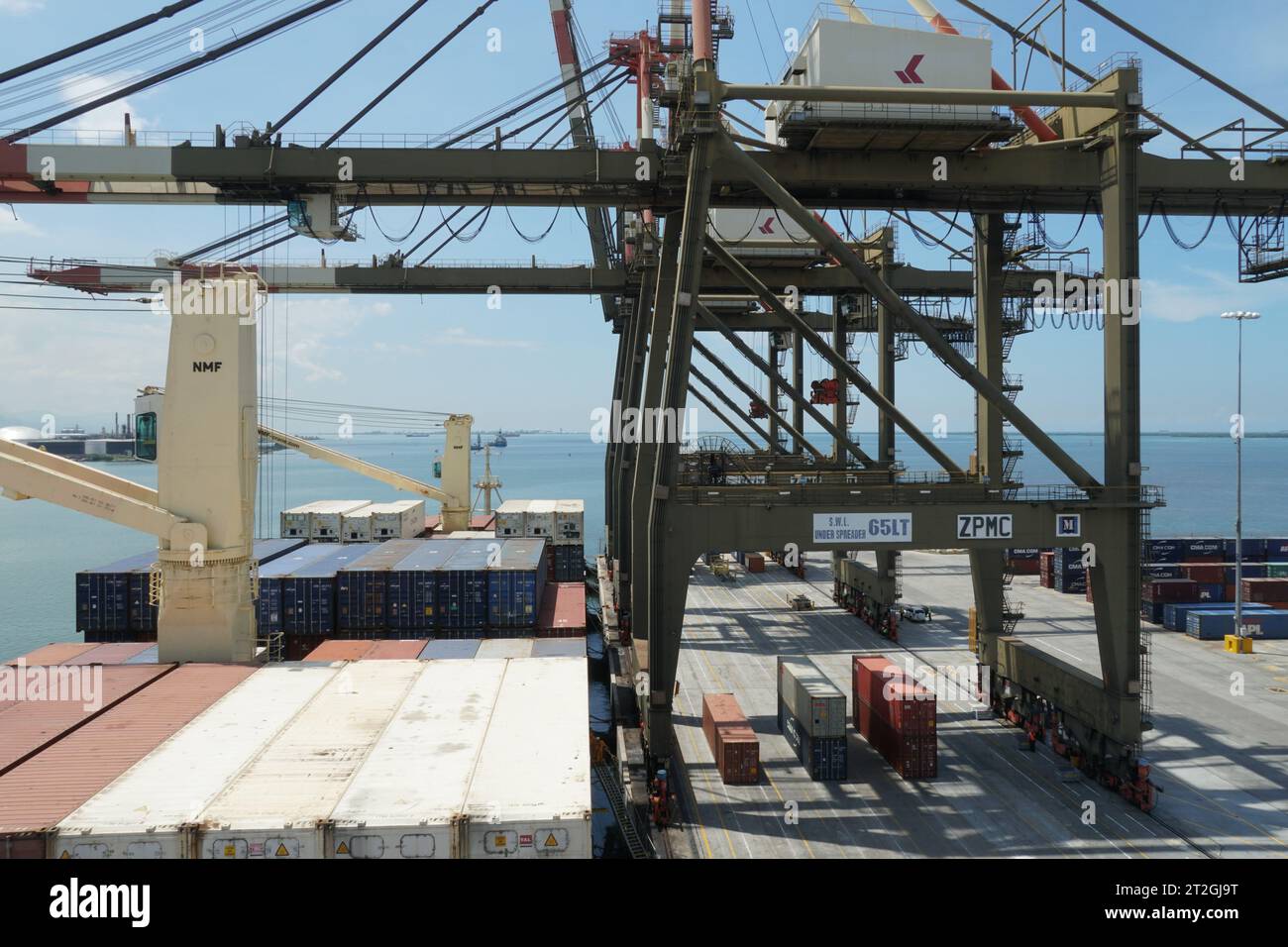 Navire porte-conteneurs équipé de grues de navire pendant l'opération de chargement et déchargement de cargaison par des grues portiques. Banque D'Images
