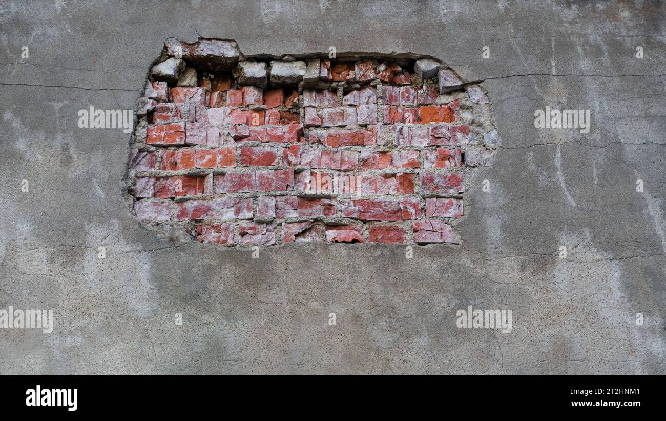 Mur de ciment fissuré avec une découpe d'une texture de brique rouge. Arrière-plan Banque D'Images