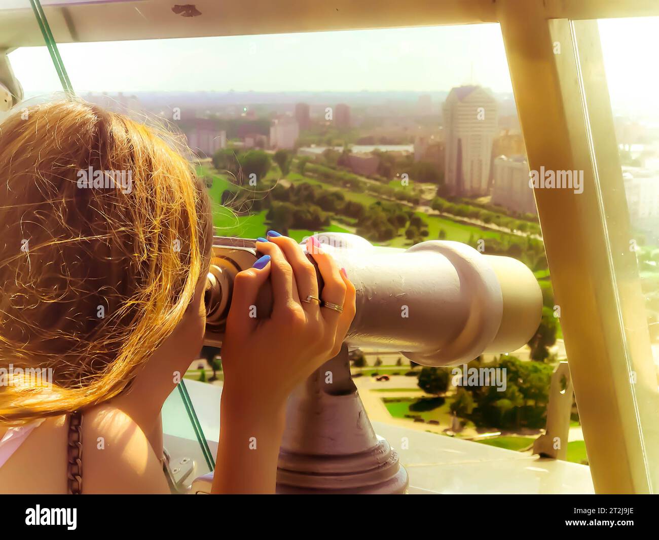 Une belle fille regarde le paysage, un panorama de la ville dans la salle d'observation, une paire de jumelles, un télescope avec un accepteur de facture sur un Banque D'Images