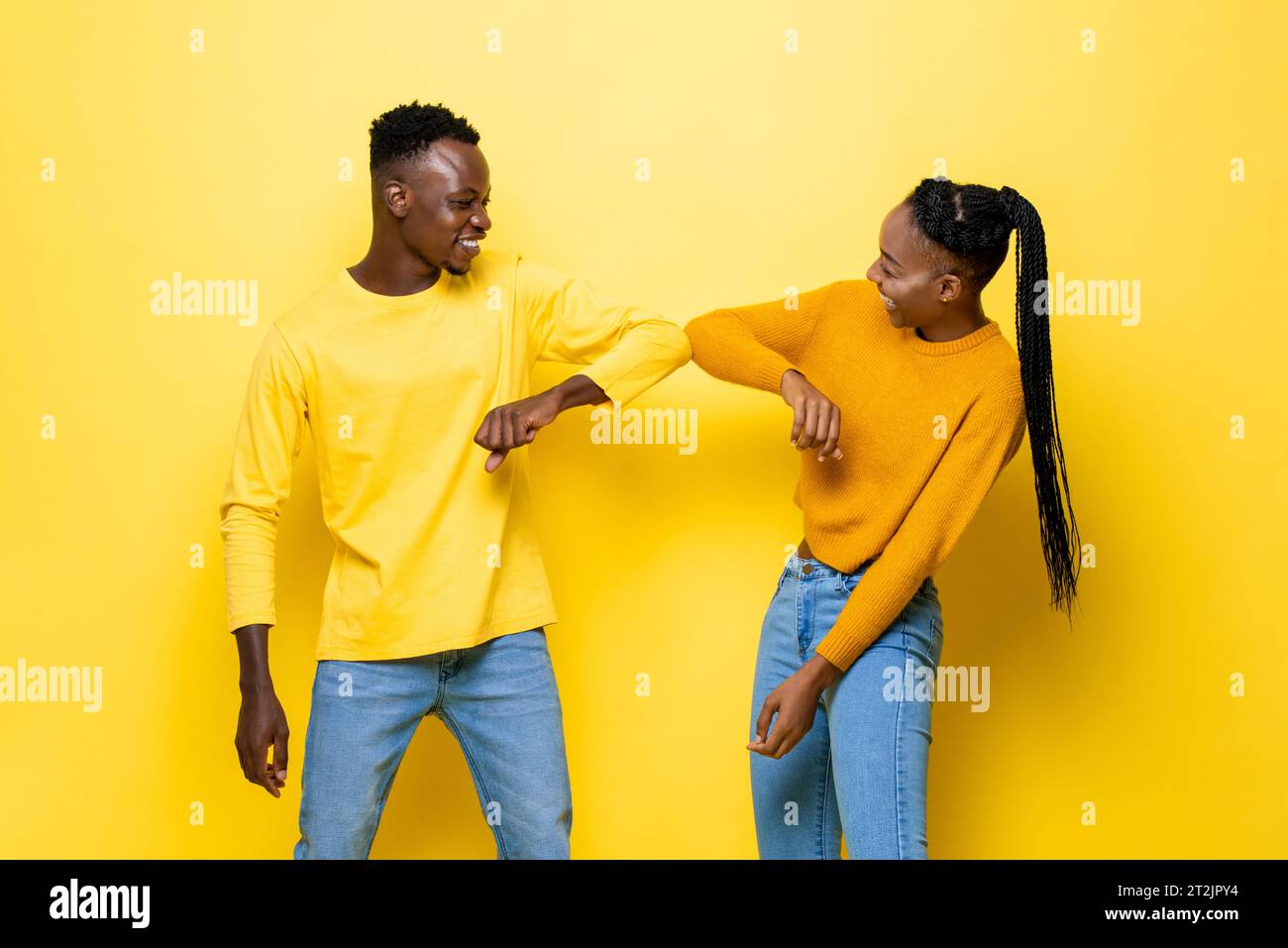 Sourire jeune couple afro-américain saluant avec bosse de coude en fond de studio isolé de couleur jaune Banque D'Images