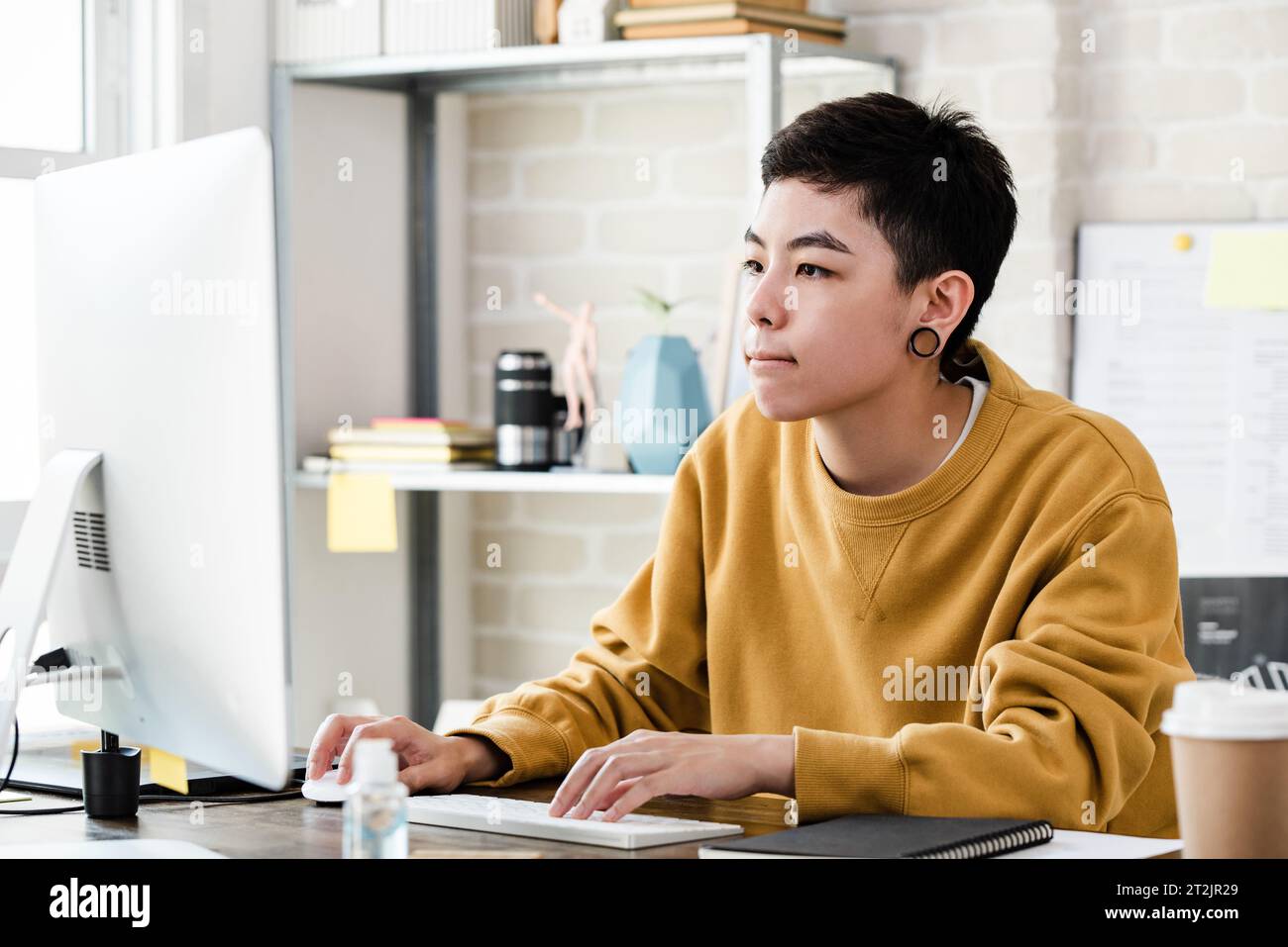 Jeune femme garçon manqué asiatique en tenue décontractée travaillant de la maison sur l'ordinateur Banque D'Images