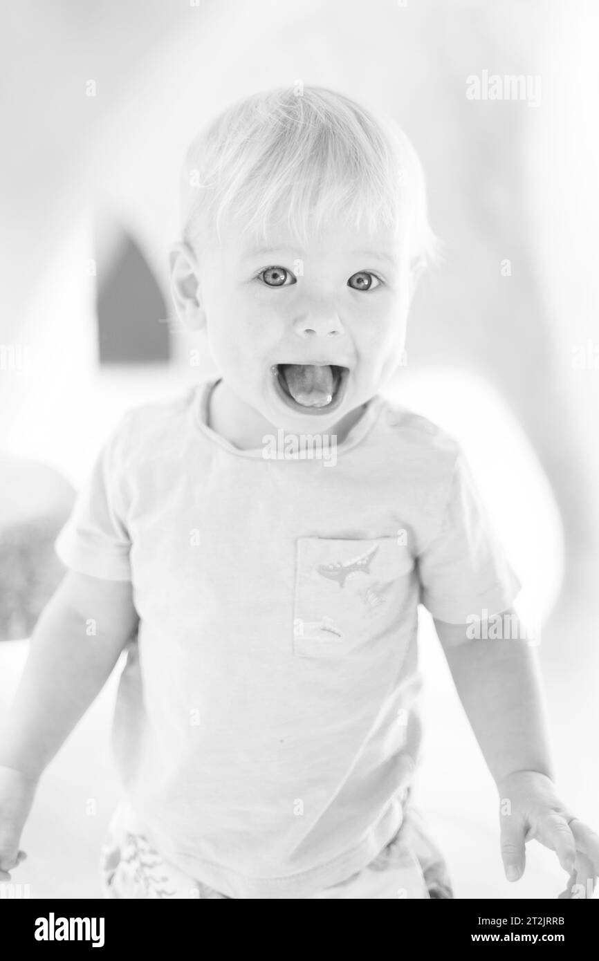 Portrait noir et blanc de l'enfant petit bébé garçon mignon jouant sur l'aire de jeux extérieure. Les tout-petits jouent dans la cour de l'école ou de la maternelle Banque D'Images