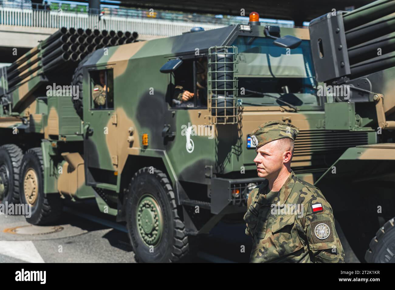 16.08.2023 Varsovie, Pologne. Soldat polonais concentré en uniforme officiel surveillant l'événement militaire en plein air. Camions militaires lourds modernes en arrière-plan. Photo de haute qualité Banque D'Images