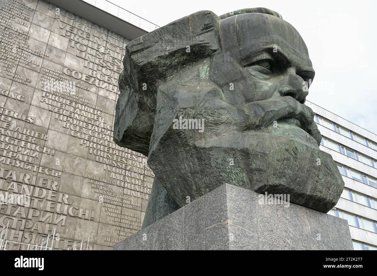 DEUTSCHLAND, Sachsen, Chemnitz, in DDR Zeiten ehemals Karl-Marx-Stadt, Karl-Marx-Monument, die 7,1 m hohe und ca. Vierzig Tonnen schwere Plastik, wurde nach einem Entwurf des sowjetischen Künstlers Lew Kerbel realisiert und 1971 eingeweiht, hintergrund Hauswandrelief mit slogan Proletarier aller Länder vereinigt Euch aus Marx Schrift Kommunistisches manifest in verschiedenen Sprachen Banque D'Images