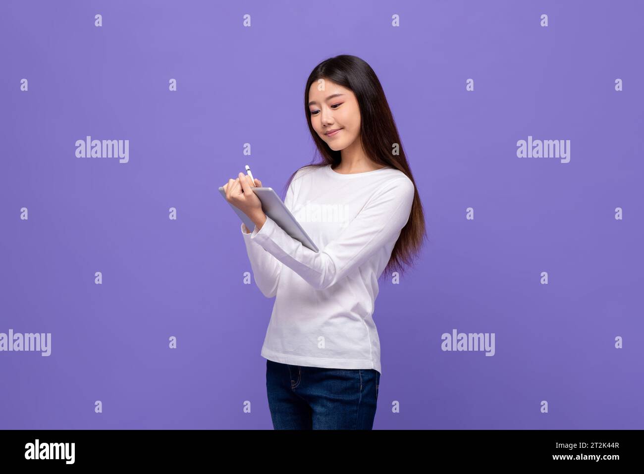 Smart jolie jeune femme asiatique à l'aide d'un ordinateur tablette dans un fond de studio violet isolé Banque D'Images
