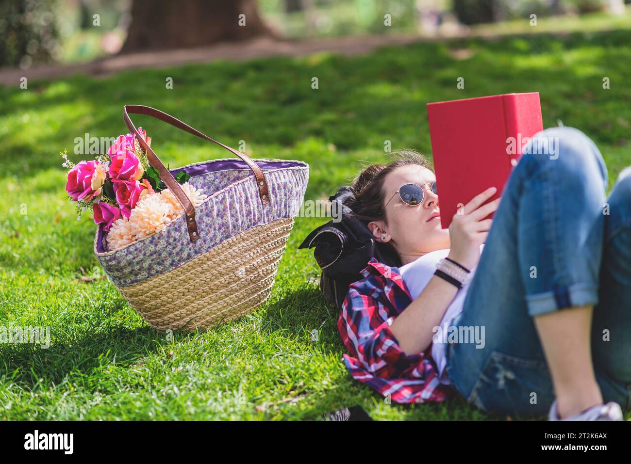 Vue de côté d'une femme heureuse hipster couchée sur l'herbe dans la journée ensoleillée a Banque D'Images