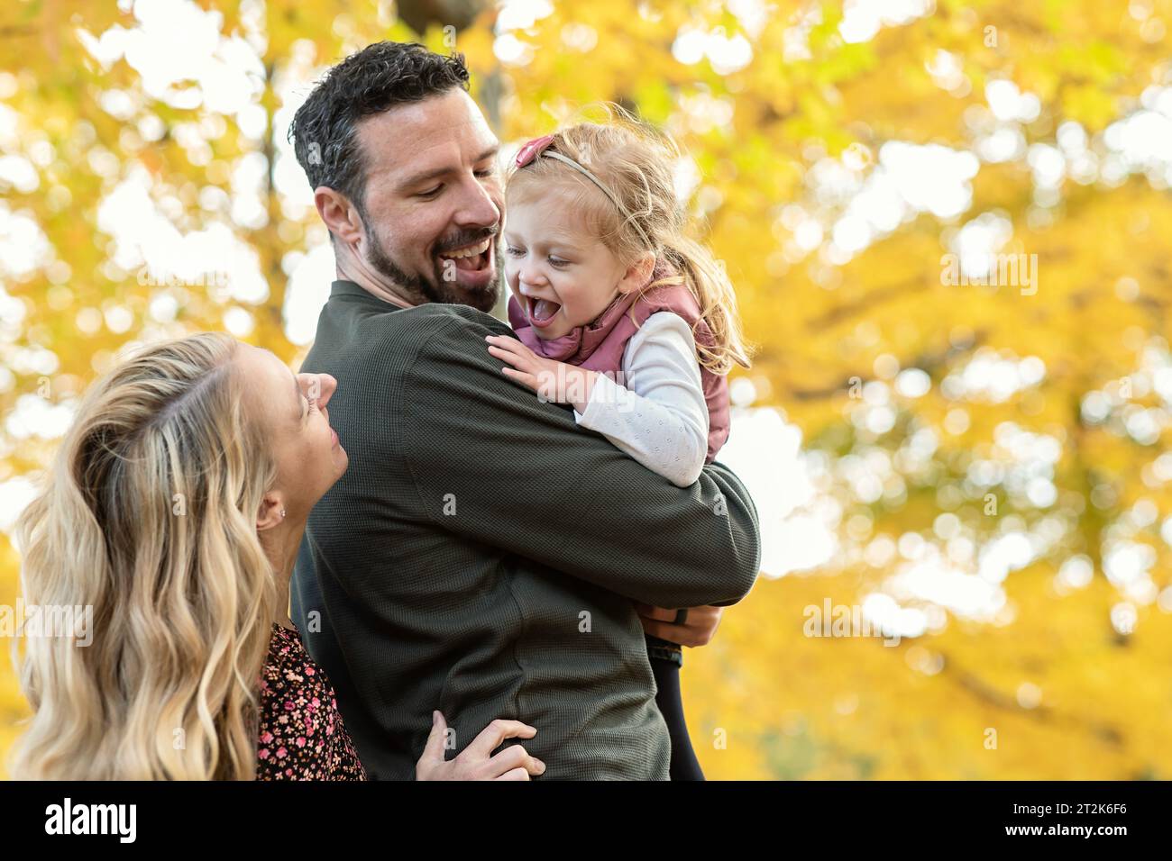 Famille de trois personnes jouant Peek a boo avec sa fille Banque D'Images