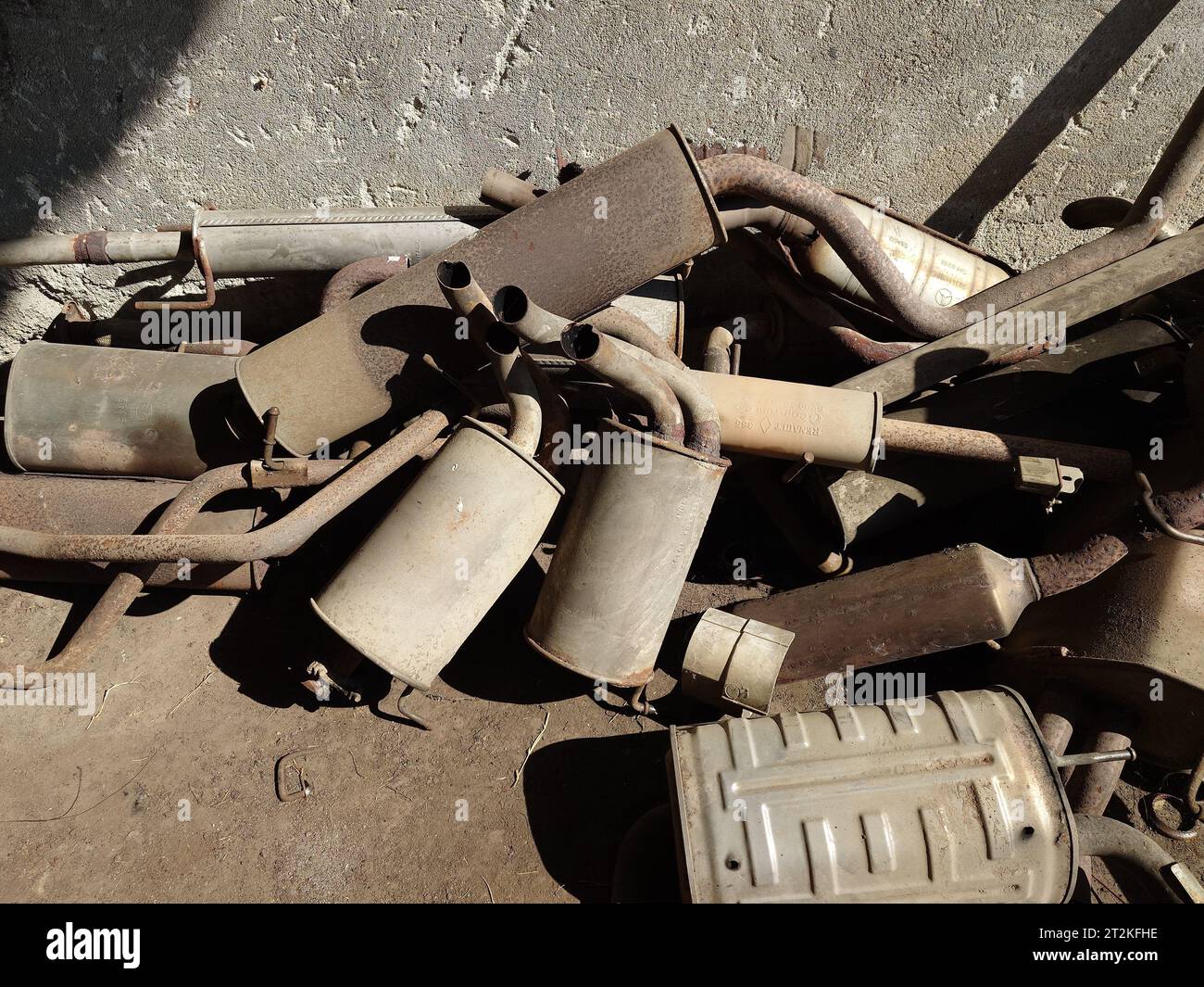 Pile de vieux pots d'échappement rouillés, silencieux ou tuyaux d'échappement dans l'arrière-cour d'un atelier de réparation automobile. Vue de dessus, pas de gens. Banque D'Images