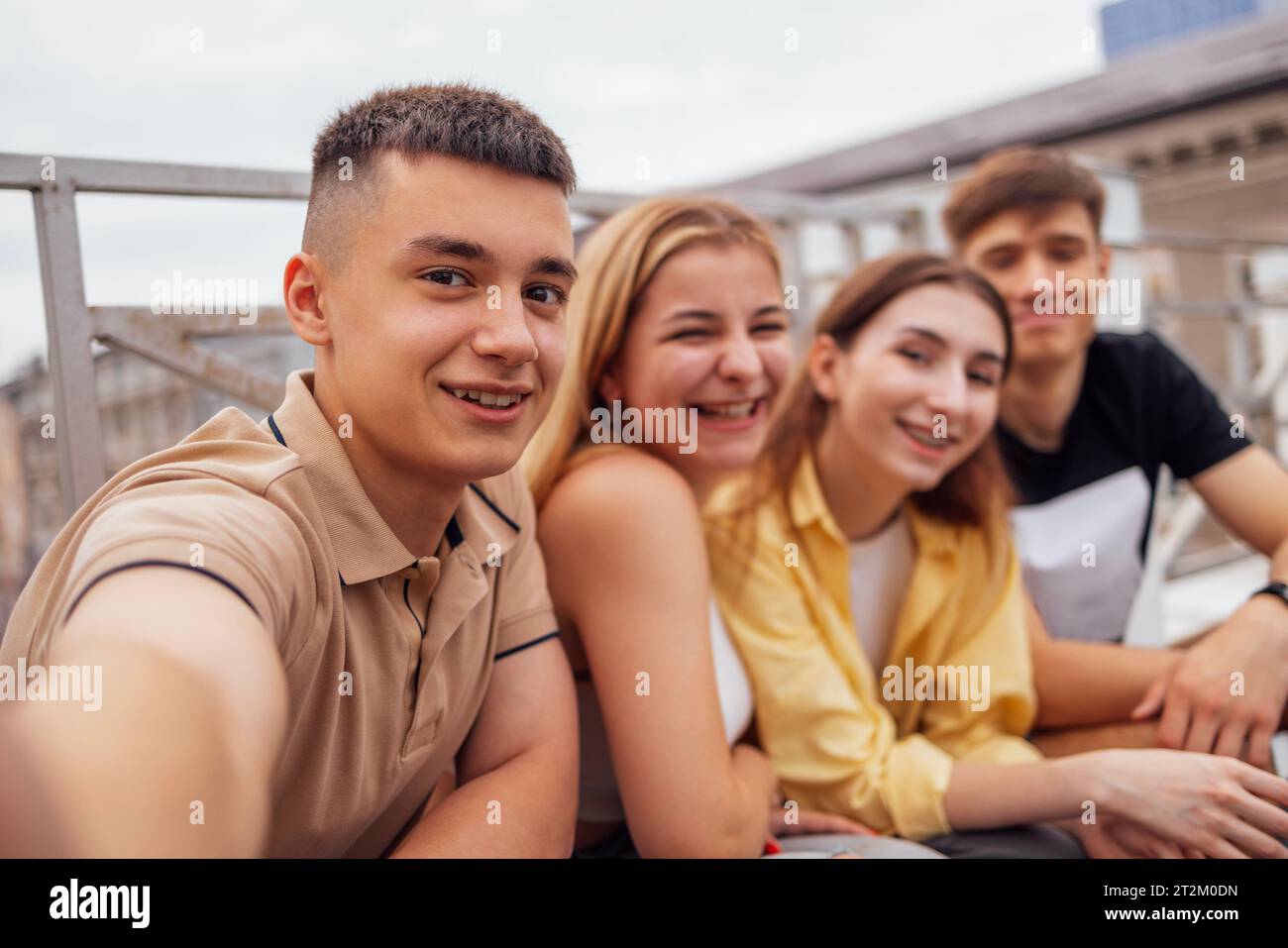 Quatre adolescents mignons prenant un selfie. Funny Friends prend une photo de soi-même sur le téléphone à l'extérieur. Garçons et filles souriants assis dans la rue. Ha Banque D'Images
