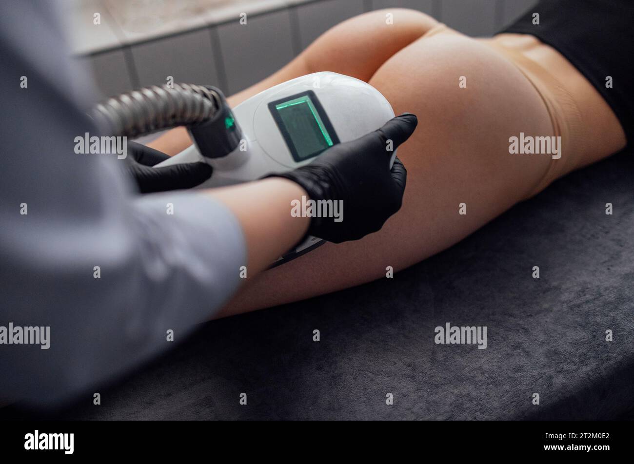 Gros plan du massage anti-cellulite de l'ensemble de l'appareil pour le massage à rouleaux sous vide. Une masseuse en gants noirs actionne une machi de correction de figure Banque D'Images