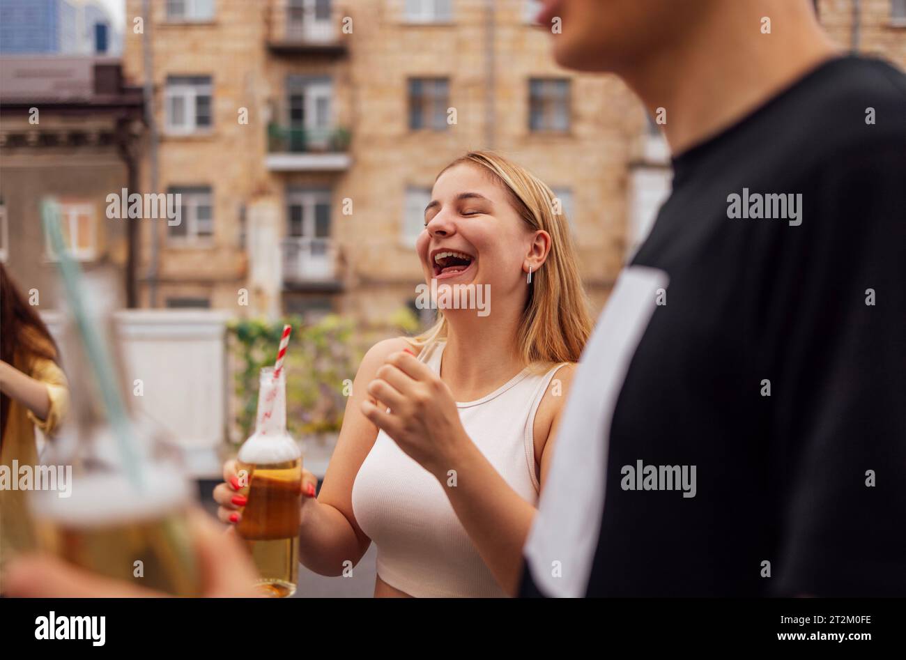 Les adolescents heureux s'amusent ensemble à l'extérieur. Les filles mignonnes et les gars en vêtements décontractés boivent des cocktails et rient. Des amis drôles bavardent et descendent le stre Banque D'Images