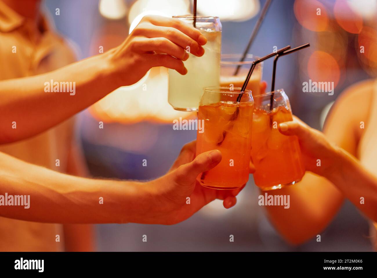 Gros plan des mains féminines et masculines tenant des verres avec des cocktails avec de la glace et en les cliquant. Les amis font un toast festif avec de délicieuses boissons aux agrumes Banque D'Images