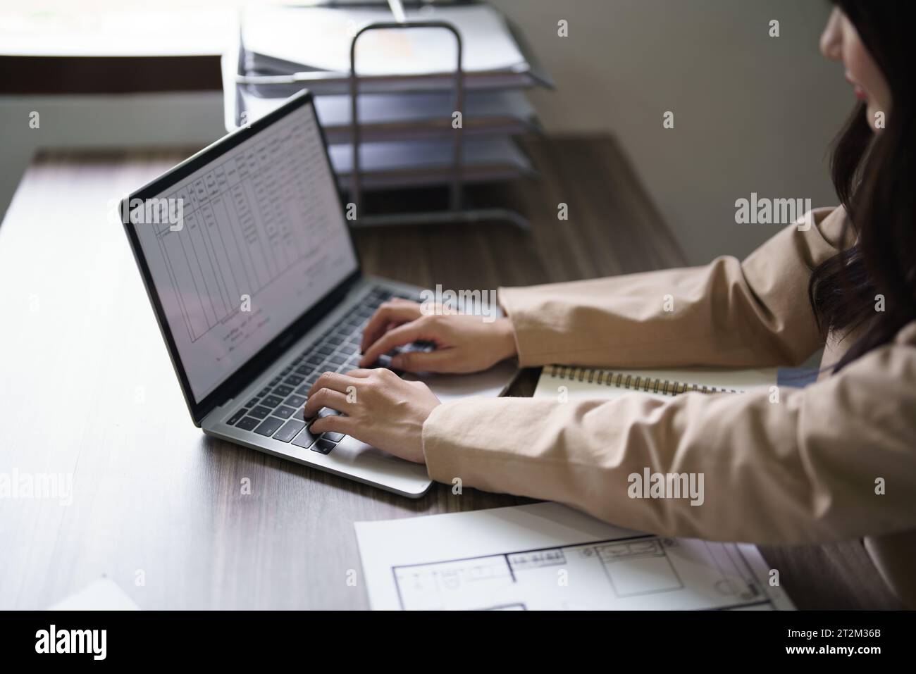 Femme architecte travaillant à taper le plan architectural sur ordinateur portable avec le plan du projet de construction. Banque D'Images