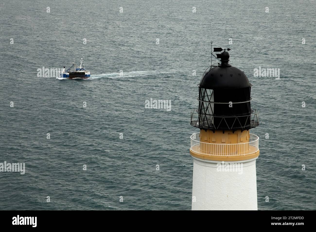 Petit bateau de pêche passant devant le phare de Maughold, île de Man. Banque D'Images