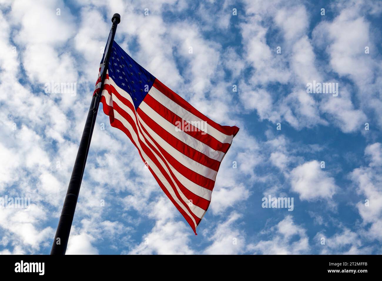 Drapeau américain volant dans le vent contre le ciel bleu avec des nuages, vue à angle bas Banque D'Images