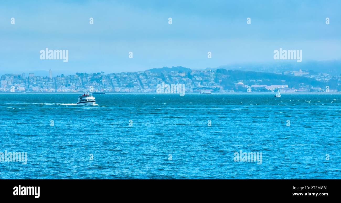 Bateau affrété aérien croisière à travers la baie de San Francisco avec des maisons lointaines sur le rivage Banque D'Images