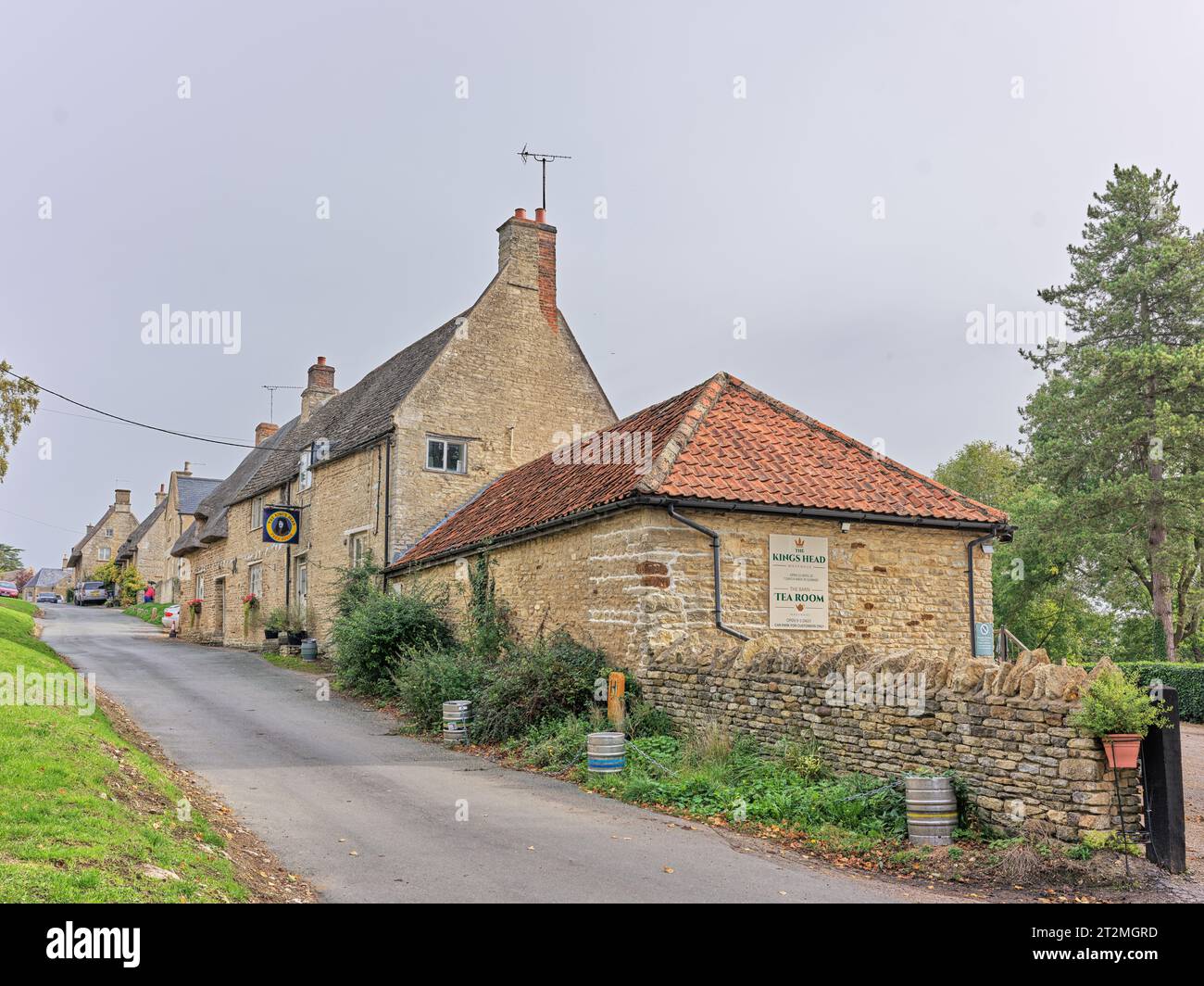 Pub construit en pierre et maisons le long d'une rue étroite dans le village anglais de Wadenhoe, Northamptonshire, Angleterre. Banque D'Images